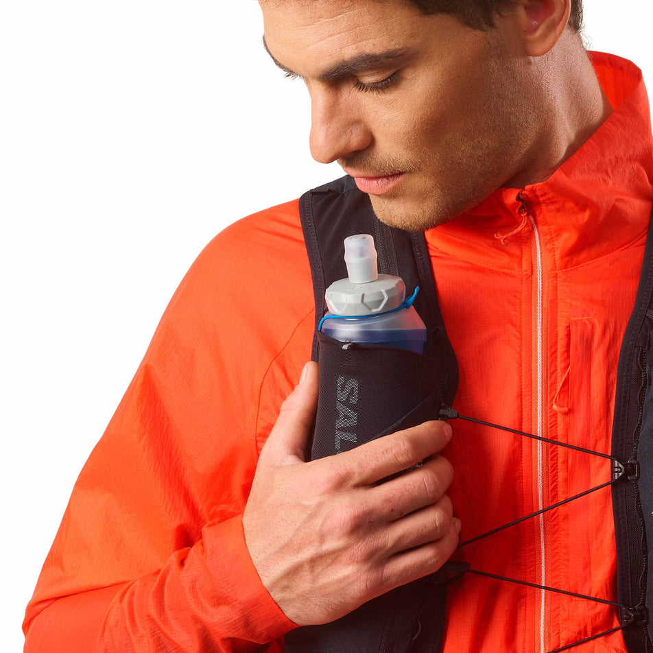 A Salomon Soft Flask 500ml/17oz Ultra 42 in the clear blue colourway stored in the front pocket of a Salomon Running Vest. (8575951929506)