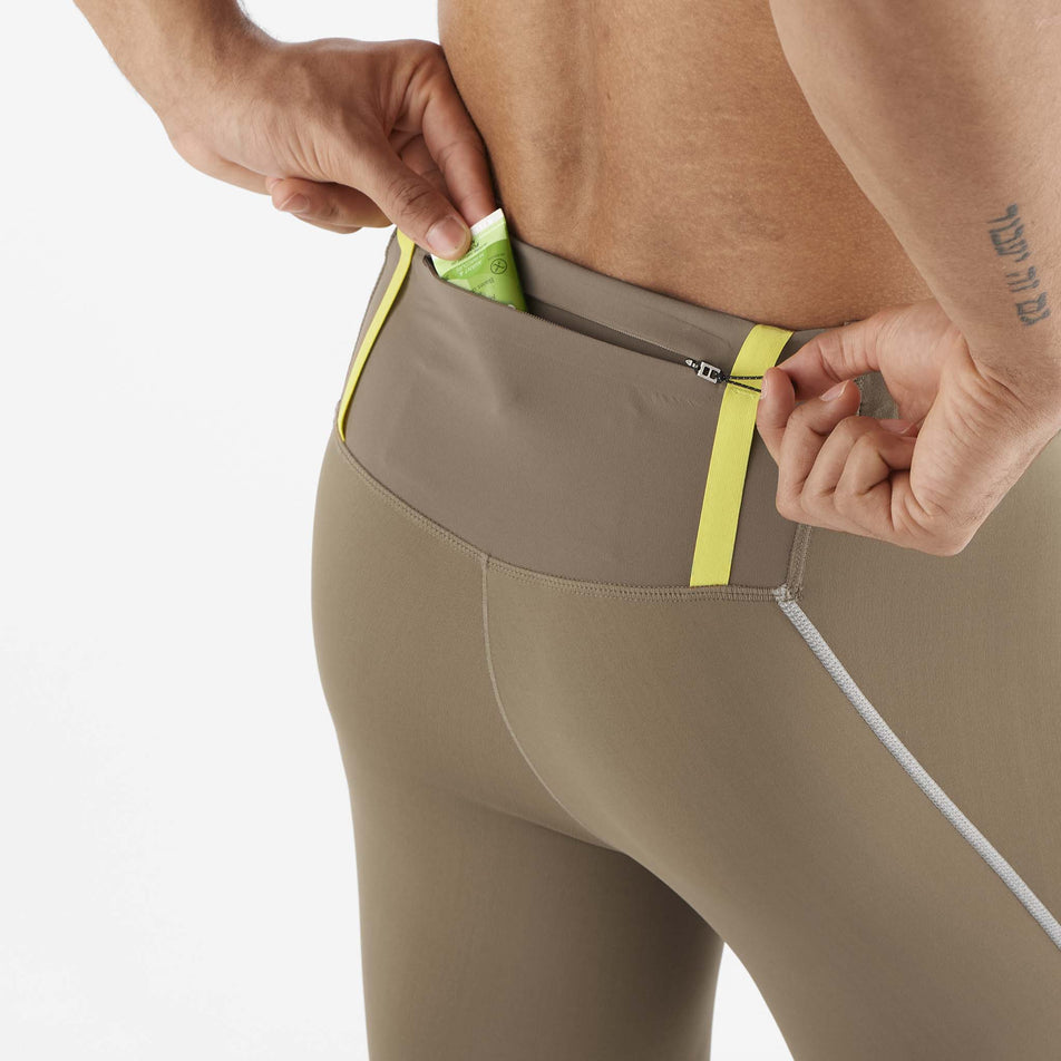 A model demonstrating that nutrition can be stored in the Salomon Men's Sense Aero Stow Tights' back zip pocket. Tights are being worn by the model. (8509599318178)