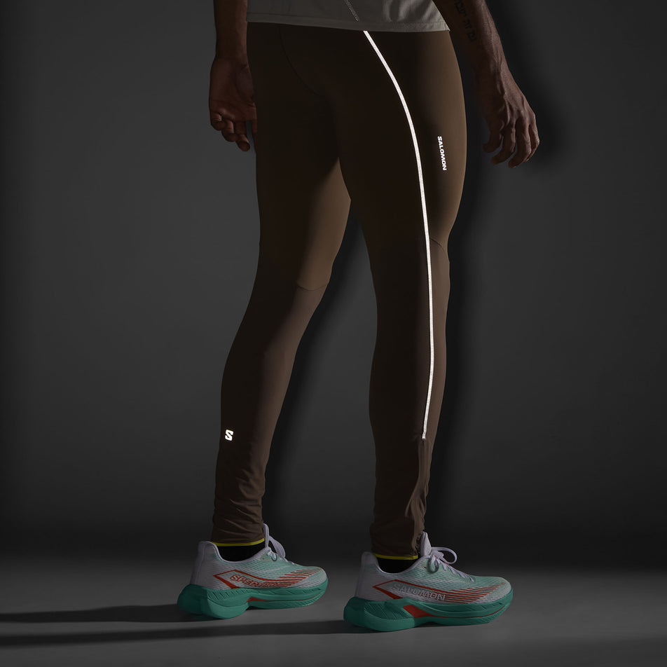 The reflectivity on the right side of the Salomon Men's Sense Aero Stow Tights. The tights are being worn by a model in low light conditions. (8509599318178)