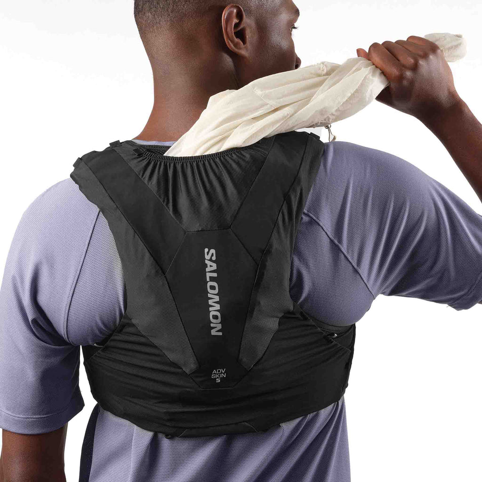 A model demonstrating the tunnel storage on the Salomon Unisex ADV Skin 5 Running Vest with flasks included in the Black colourway. (8575893307554)