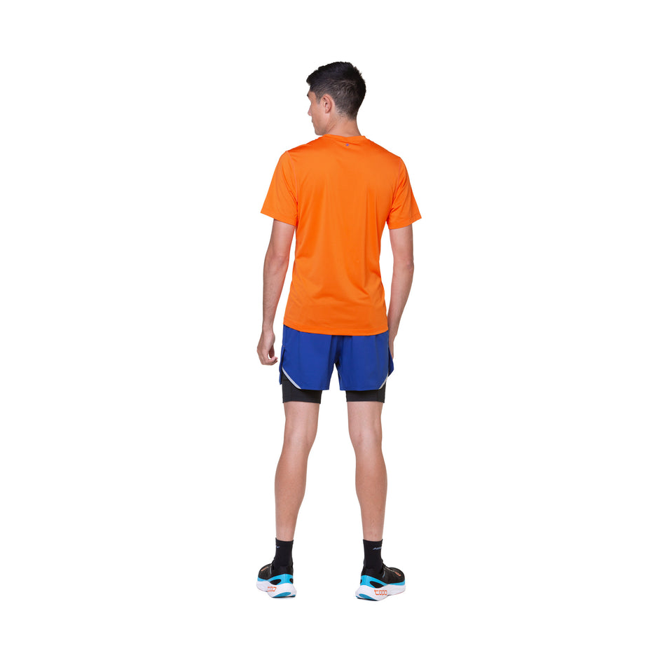 Back view of a model wearing the Ronhill Men's Tech S/S Tee in the Cardinal Orange/Orange colourway. Model is also wearing socks, shorts and shoes. (8490372726946)