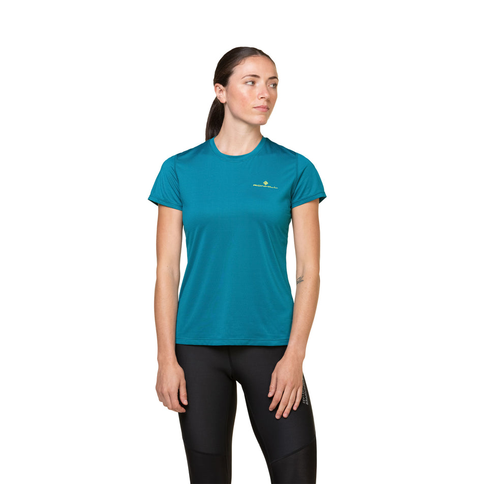 Front view of a model wearing the Ronhill Women's Tech S/S Tee in the Marine/Acid colourway. Model is also wearing leggings. (8490105634978)