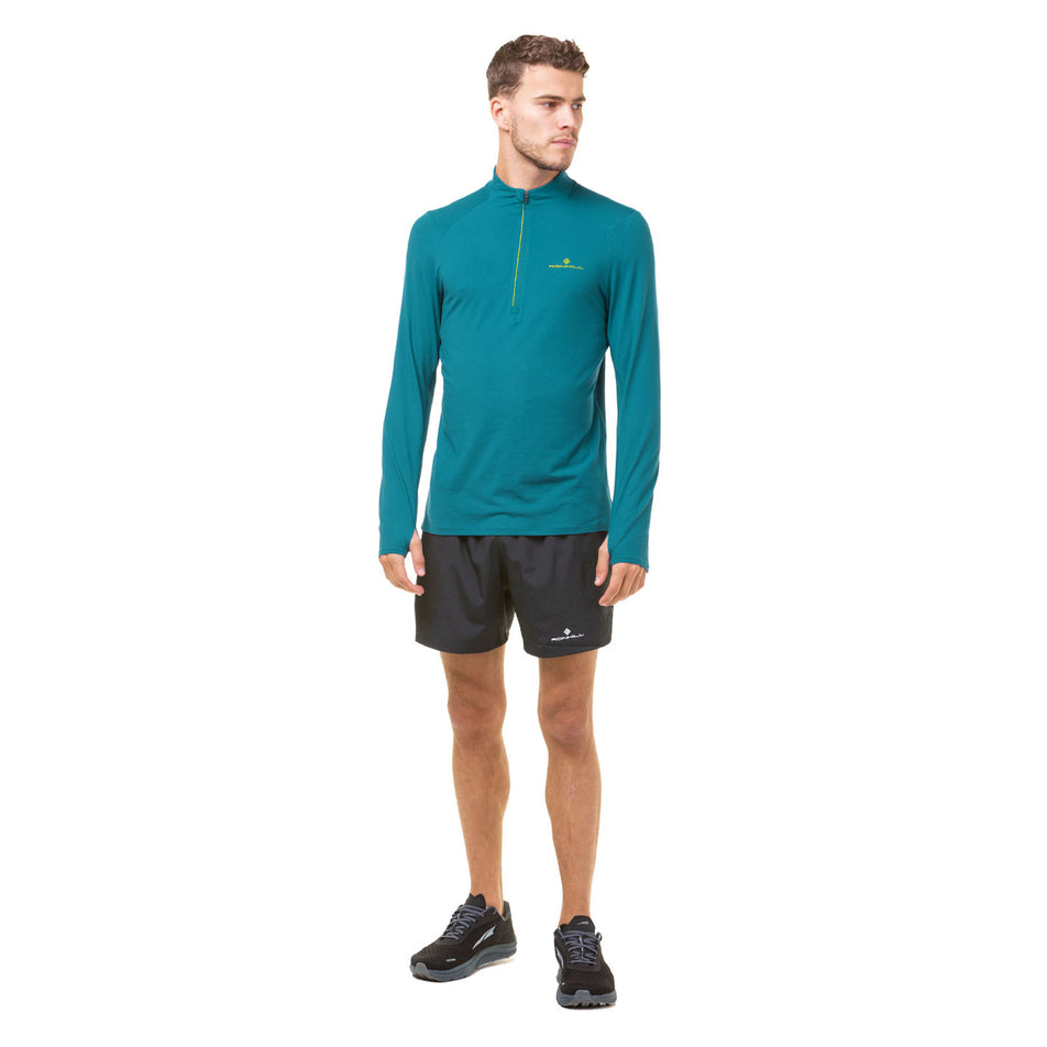 Front view of a model wearing a Ronhill Men's Core Thermal 1/2 Zip in the Deep Teal/Acid colourway. Model is also wearing shorts and shoes. (8470840705186)