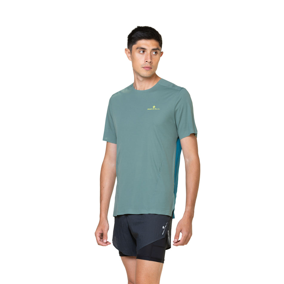 Front view of a model wearing a Ronhill Men's Tech Race S/S Tee in the Dark Sage/Deep Teal colourway. Model is also wearing shorts. (8470668345506)