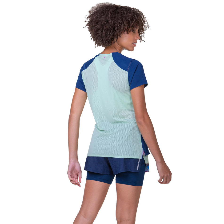 Back view of a model wearing a Ronhill Women's Tech Race S/S Tee in the Dark Navy/Honeydew colourway. Model is also wearing Ronhill shorts. (8270470578338)