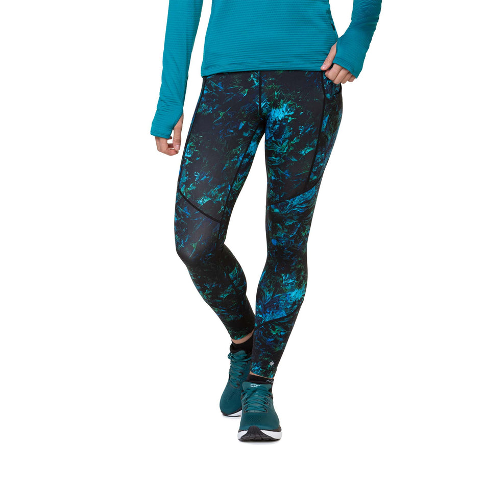 Front view of a model wearing the Ronhill Women's Tech Tight in the Marine Amazon colourway. Model is also wearing shoes and a top. (8489995141282)