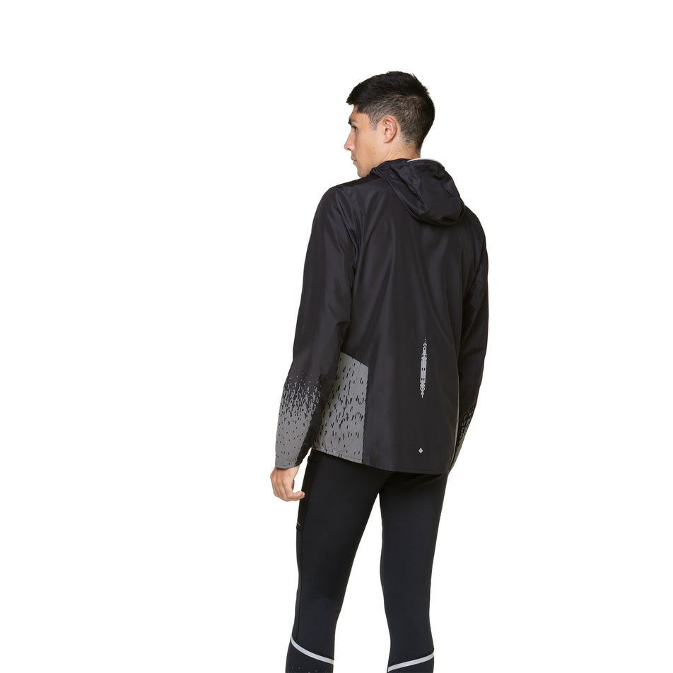 Back view of a model wearing a Ronhill Men's Tech Reflect Jacket in the Black/Reflect colourway. Model is also wearing leggings.  (8490194731170)