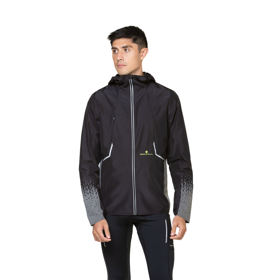 Front view of a model wearing a Ronhill Men's Tech Reflect Jacket in the Black/Reflect colourway. Model is also wearing leggings.  (8490194731170)