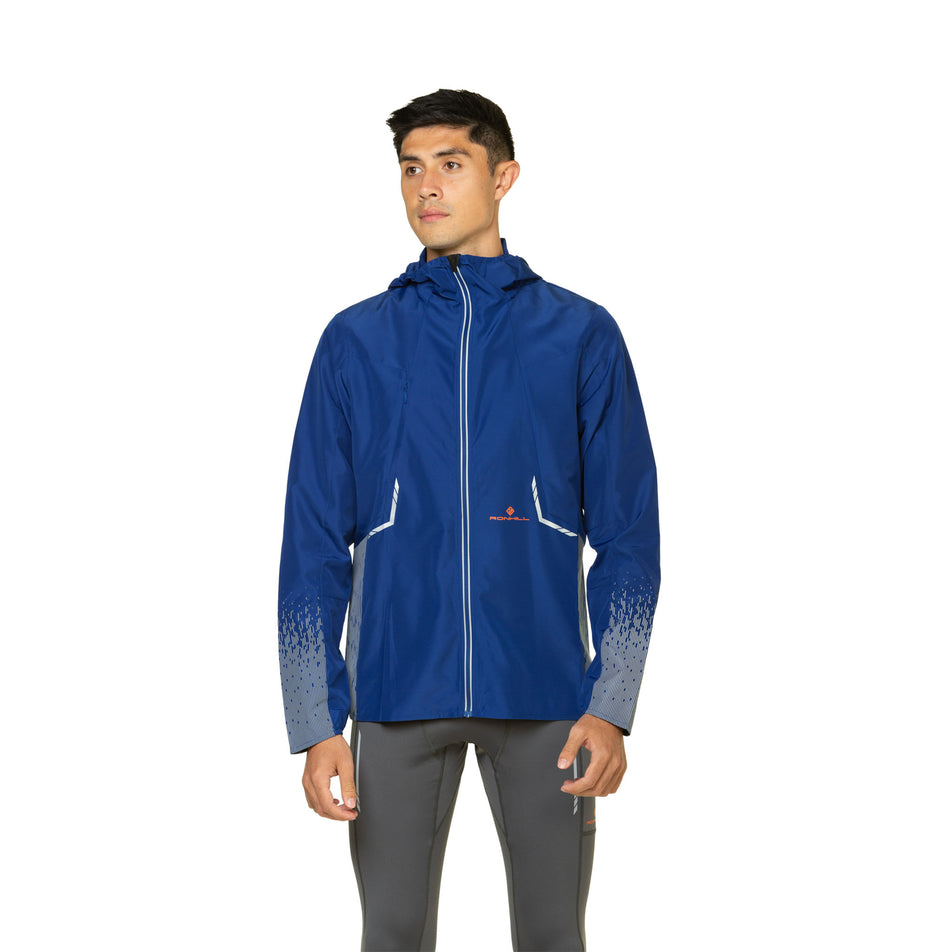 Front view of a model wearing a Ronhill Men's Tech Reflect Jacket in the Ocean/Reflect colourway. Model is also wearing leggings.  (8469614395554)