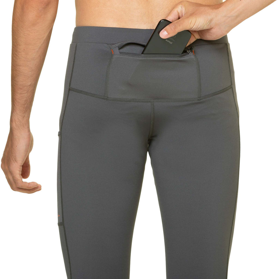 A model demonstrating that a phone can be stored in the back pocket of the Ronhill Men's Tech Reflect Tight in the Iron/Reflect colourway. (8490232447138)