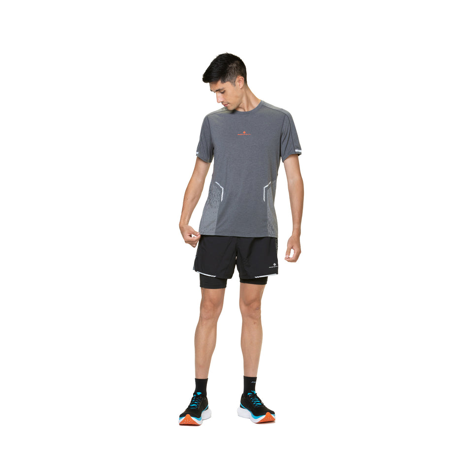 Front view of a model wearing a Ronhill Men's Tech Reflect S/S Tee in the Iron/Reflect colourway. Model is also wearing socks, shoes and shoes. (8490228940962)