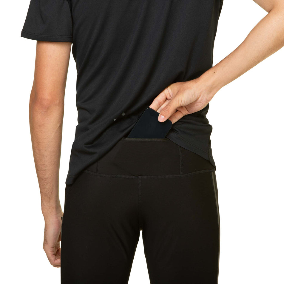 A model demonstrating that a phone can be stored in the back zip pocket of the Ronhill Men's Tech GORE-TEX Windstopper Tight. Tights are being worn by the model. (8490245587106)