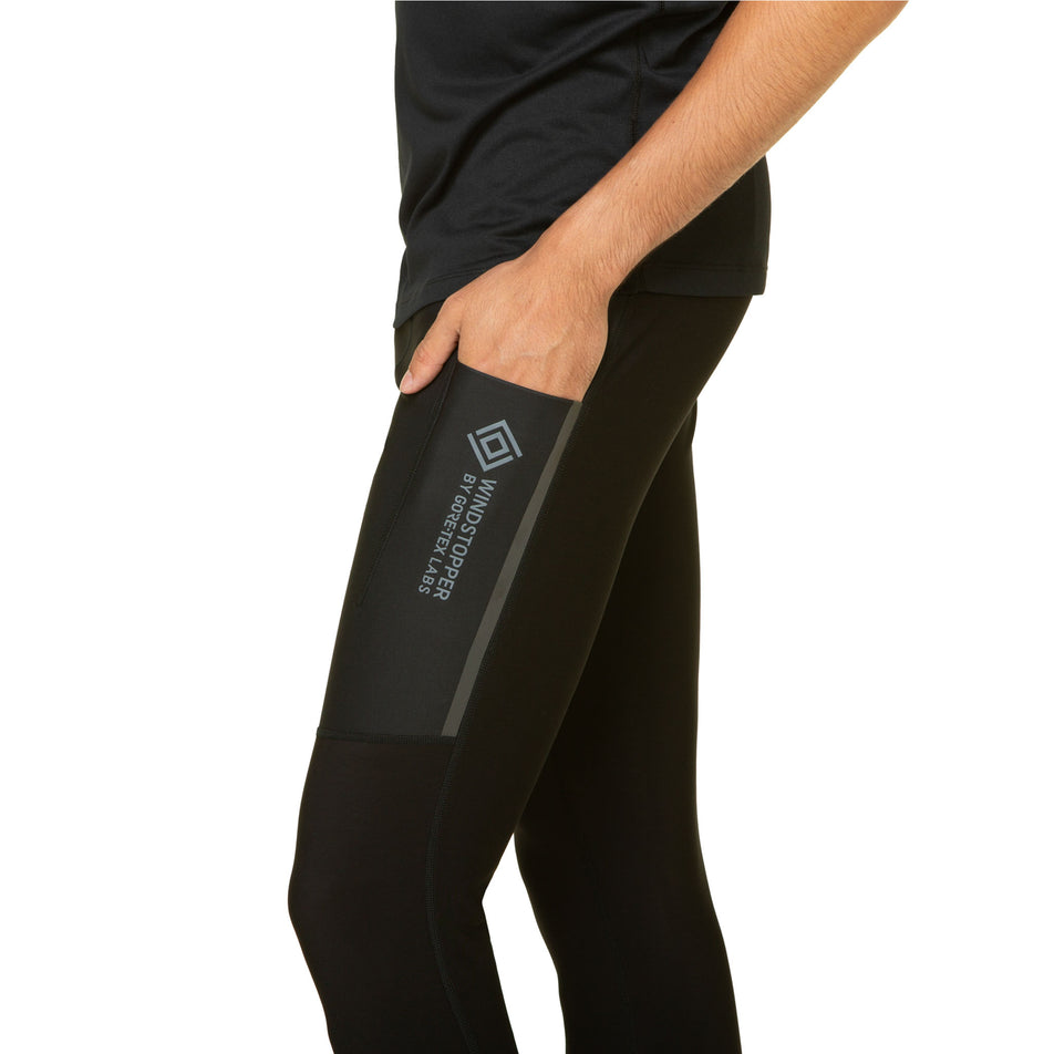 A model demonstrating the side pocket on the left-thigh of the Ronhill Men's Tech GORE-TEX Windstopper Tight. Tights are being worn by the model. (8490245587106)