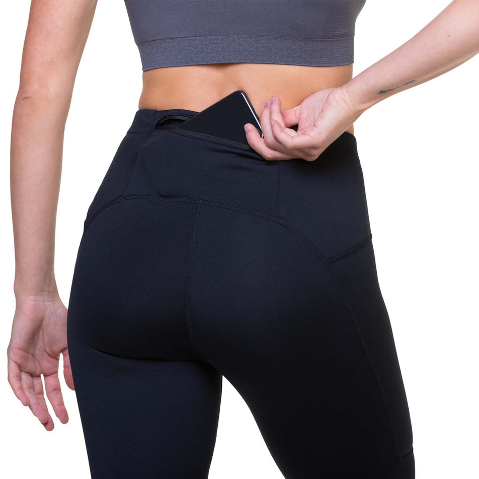 A model highlighting that a phone can be stored in the zipped back pocket of the Ronhill Women's Tech Reflect Tight (8469261287586)