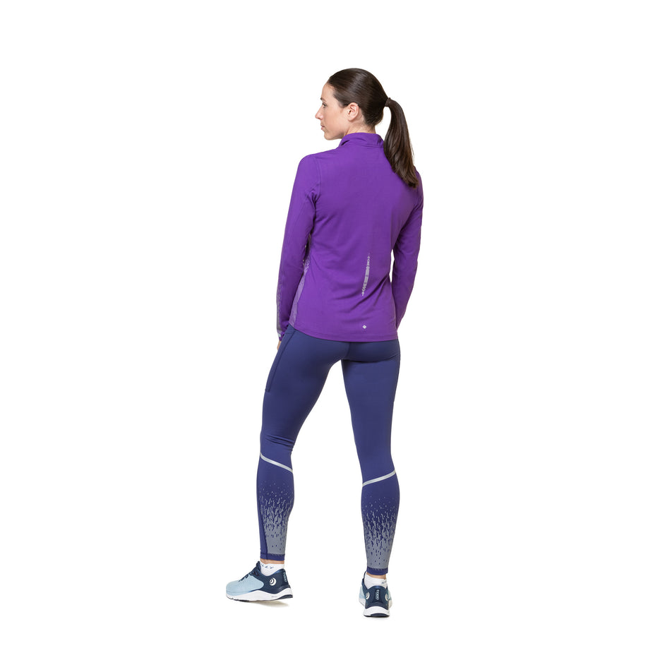 Back view of a model wearing the Ronhill Women's Tech Reflect Tight in the Deep Ocean/Reflect colourway. Model is also wearing shoes and a long-sleeve top. (8489759604898)