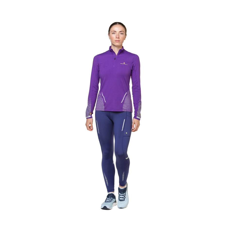 Front view of a model wearing the Ronhill Women's Tech Reflect Tight in the Deep Ocean/Reflect colourway. Model is also wearing shoes and a long-sleeve top. (8489759604898)