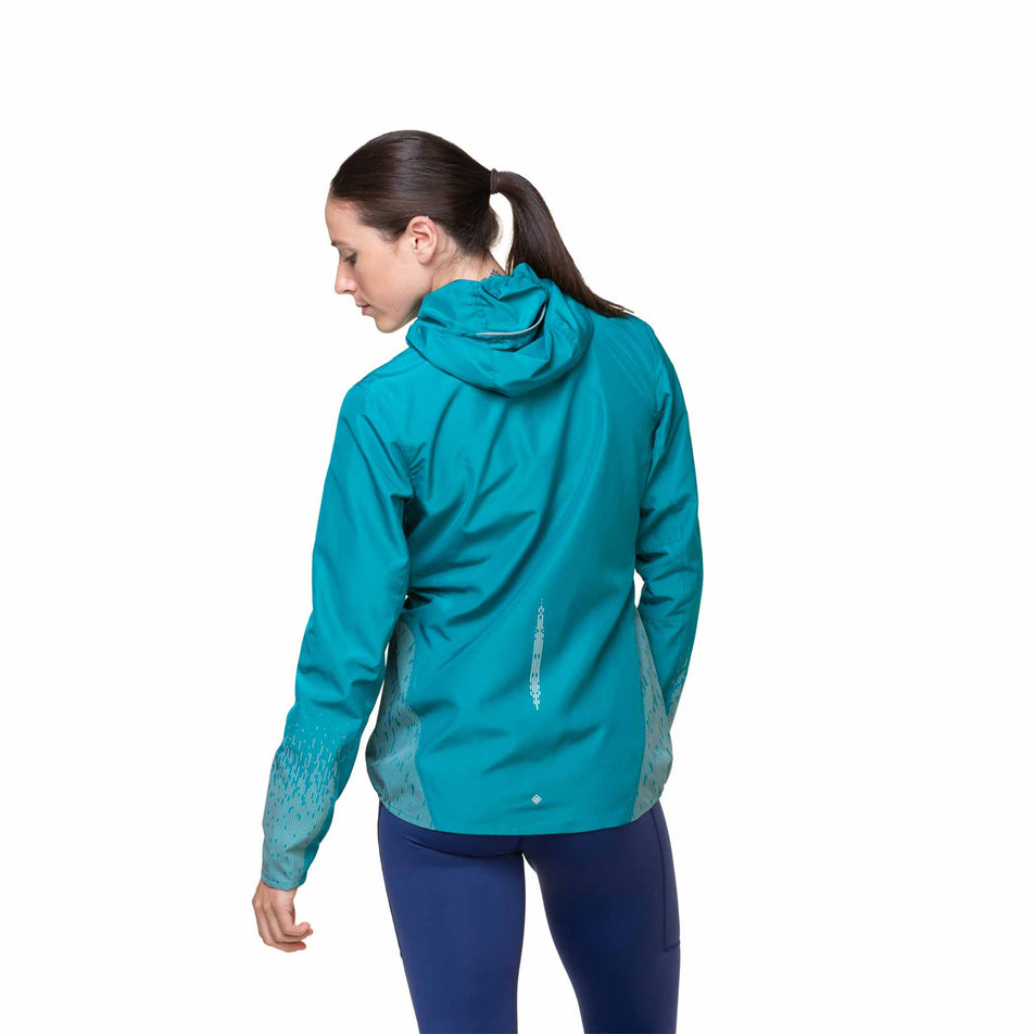 Back view of a model wearing a Ronhill Women's Tech Reflect Jacket in the Marine/Reflect colourway. Model is also wearing leggings.  (8469205090466)