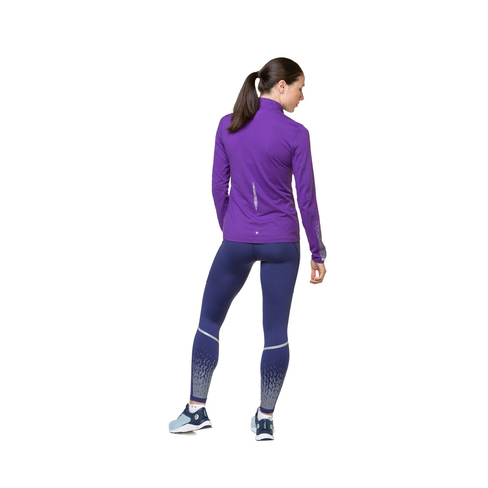 Back view of a model wearing a Ronhill Women's Tech Reflect 1/2 Zip in the Regal Purple/Reflect colourway. Model is also wearing shoes and tights. (8489687449762)