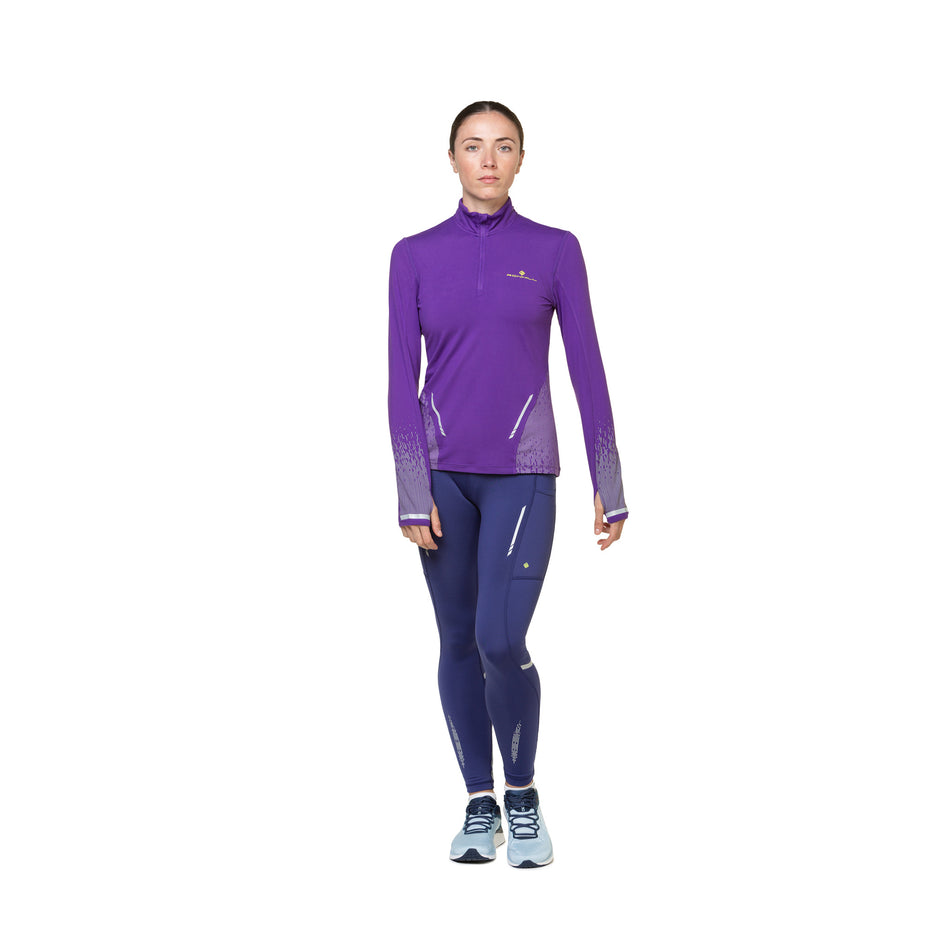 Front view of a model wearing a Ronhill Women's Tech Reflect 1/2 Zip in the Regal Purple/Reflect colourway. Model is also wearing shoes and tights. (8489687449762)