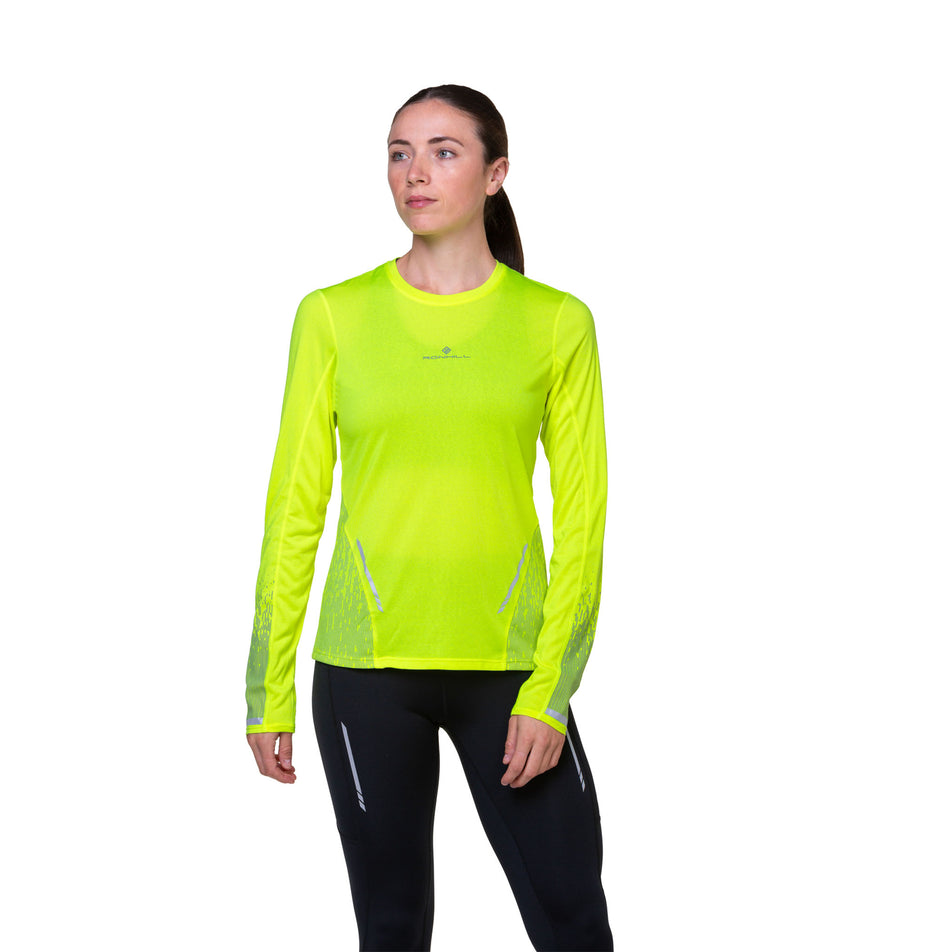 Front view of a model wearing a Ronhill Women's Tech Reflect L/S Tee in the Fluo Yellow/Reflect colourway. Model is also wearing tights. (8489706717346)