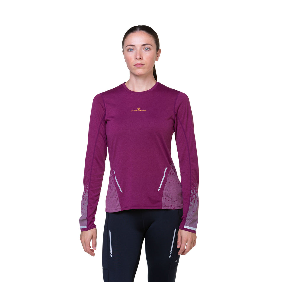 Front view of a model wearing a Ronhill Women's Tech Reflect L/S Tee in the Blackcurrant/Reflect colourway. Model is also wearing tights. (8489740435618)