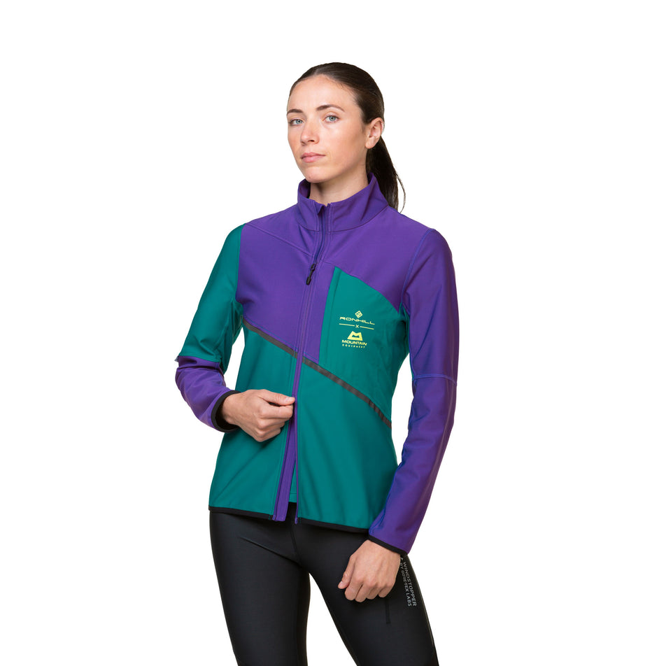 Front view of a model wearing a Ronhill Women's Tech GORE-TEX Windstopper Jacket in the Marine/Regal Purple colourway. Model is also wearing leggings. (8489773990050)