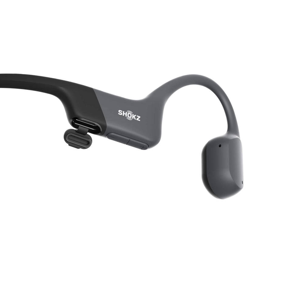 Close-up of the right earbud from a pair of Shokz Unisex OpenRun Wireless Bone Conduction Headphones in the Black colourway. The image shows the USB-Type C charging port.  (8541472653474)